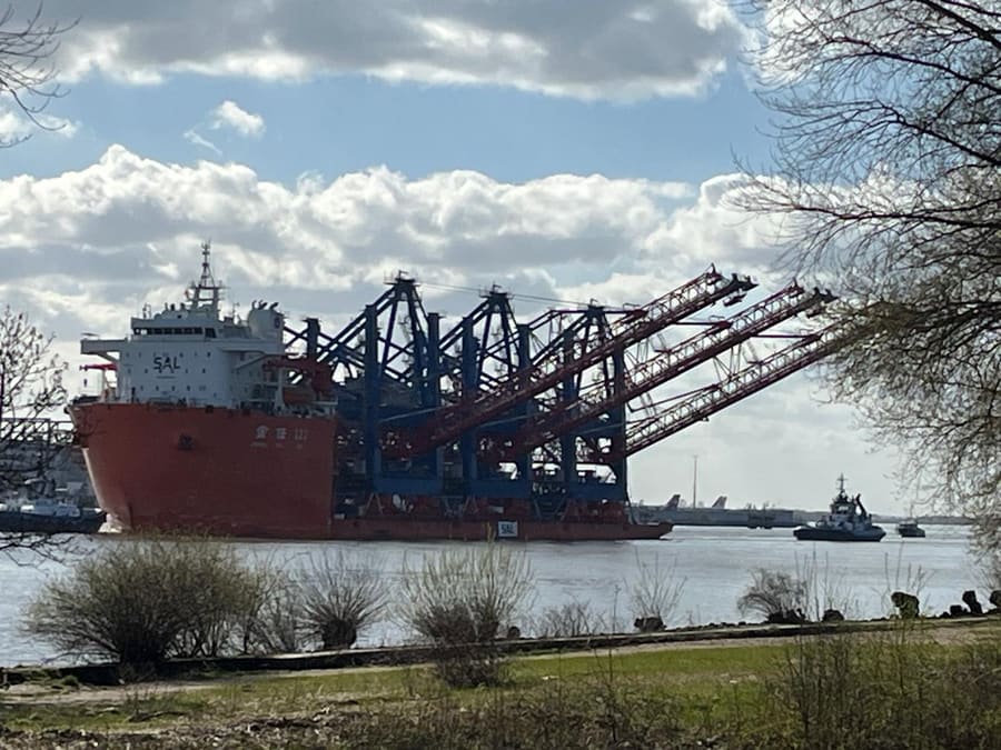 Blick über die Elbe auf ein Frachtschiff mit Containerbrücken im Hamburger Hafen