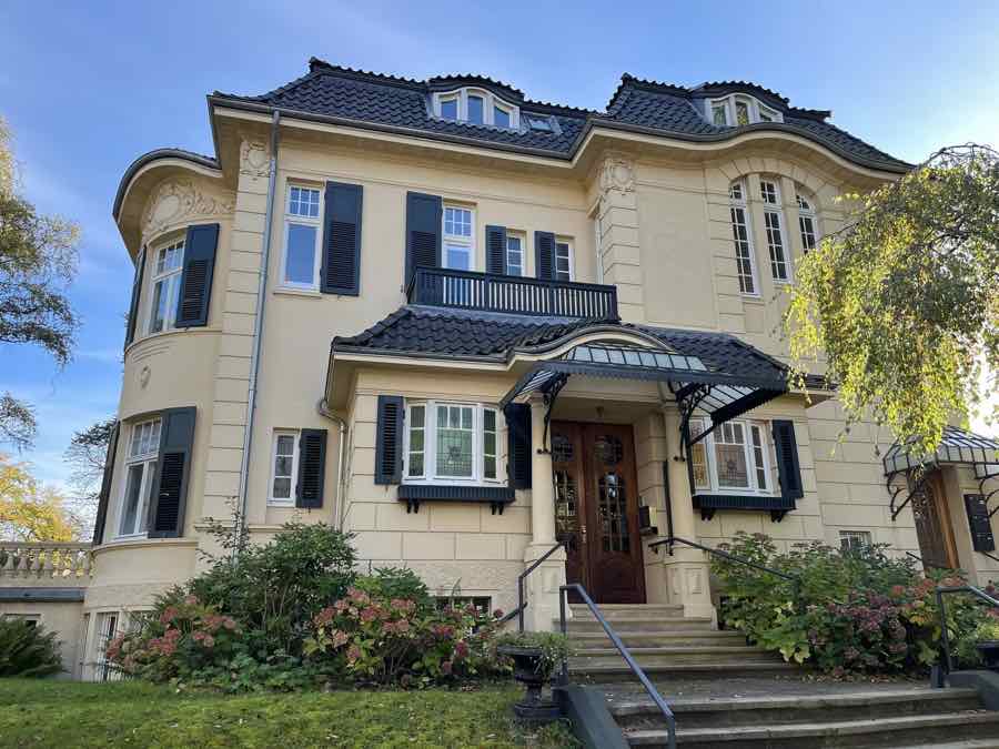 Hamburger Stadtvilla mit gelber Fassade, dunklen Fensterläden und Treppenaufgang
