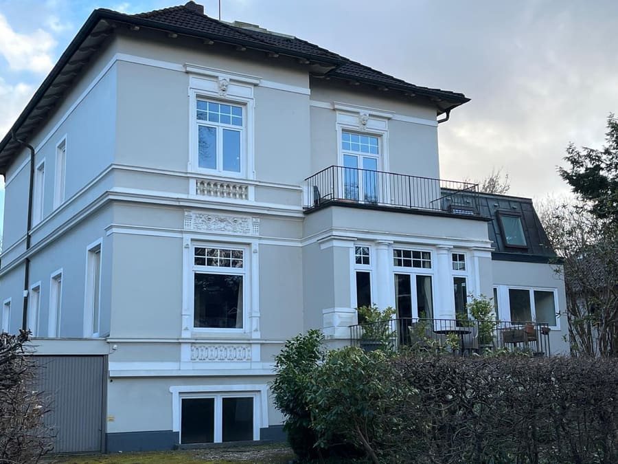 Weiße Stadtvilla mit Stuckfenstern, Balkon und Vorgarten